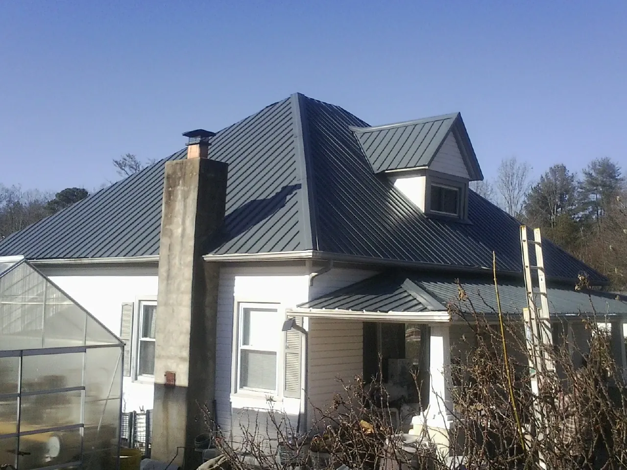 Dark blue standing seam metal roof on a white farmhouse with dormer — Slate & Tile Roof Repair by Roofing Brothers in Chantilly