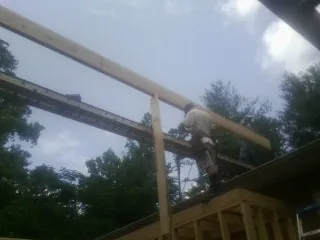 Carpenter setting a ridge beam over a new addition frame — Ice Dam Removal by Roofing Brothers in Chantilly