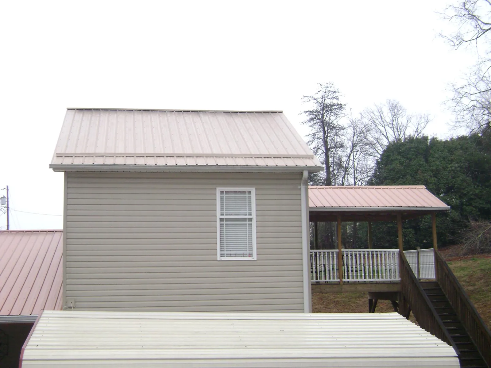 Tan metal roofs on a two story addition and attached porch, from a Roof Replacement job in Chantilly