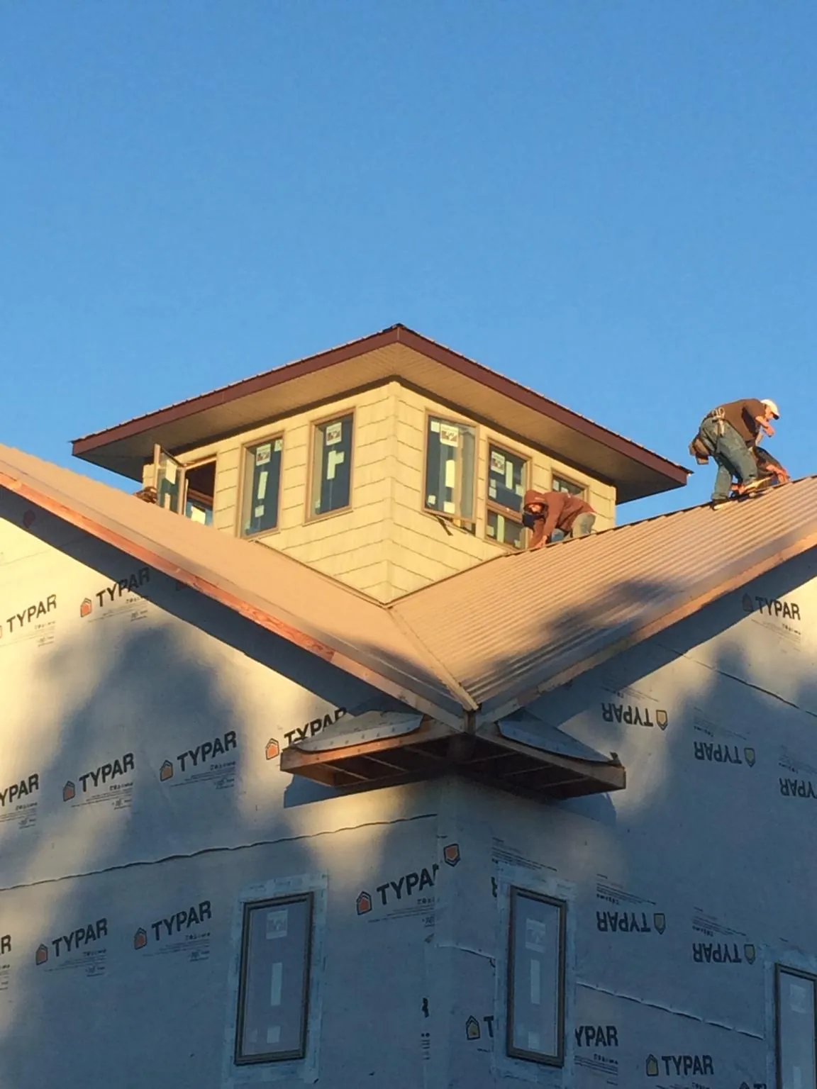 Roofers working around a rooftop cupola on a new metal roof at sunset — Roof Waterproofing in Chantilly by Roofing Brothers